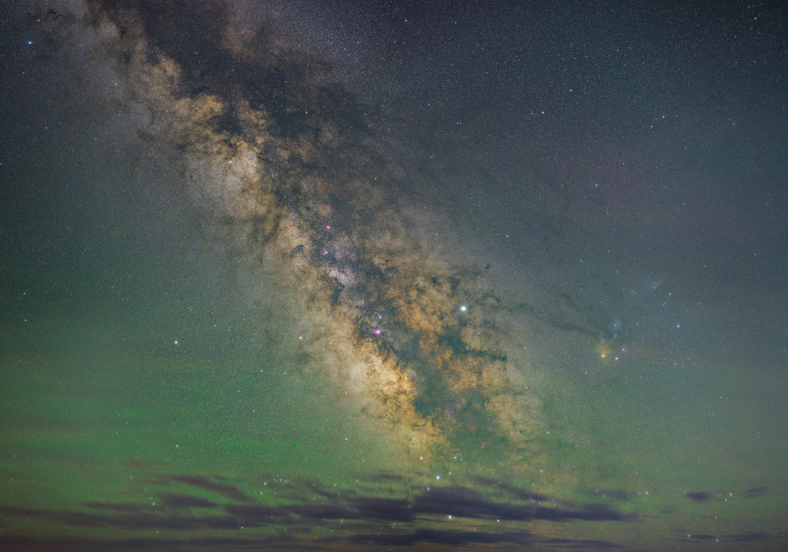 A galaxyscape. There is a green tint to the sky, and a few stars are visible. There is a gray galaxy with a yellow aura in the center.